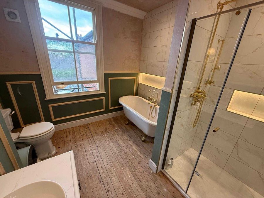 Roll-top bath and brass shower enclosure in a period bathroom